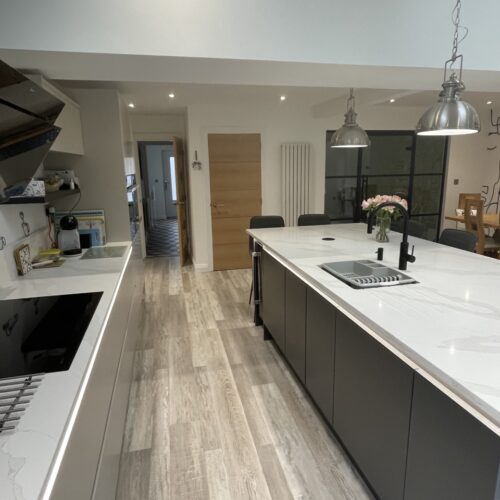 A handleless rail kitchen. Colour Savanna along the straight run in background and the kitchen island is in graphite.
